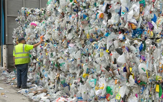 Man examines bales of plastic waste bottles