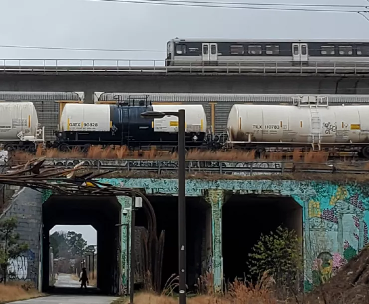 A MARTA train crosses a bridge above a walking trail