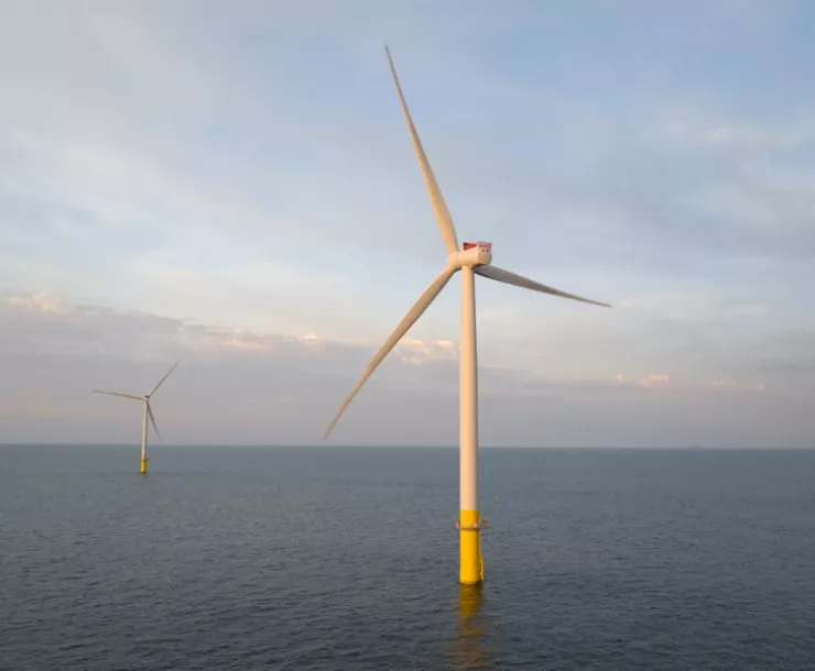 A photograph of two offshore windmills in the open ocean.