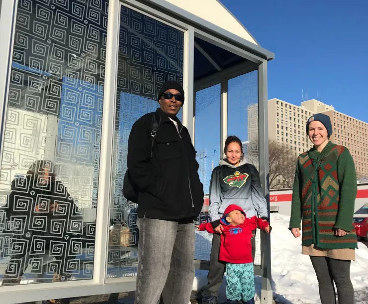 riders stand at a Metro Transit bus stop on a sunny winter day