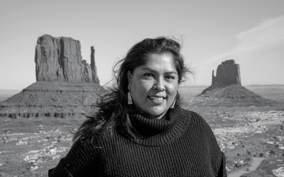 Davina Smith wears a black turtleneck and stands in front of two rock formations in Monument Valley, Utah. _______